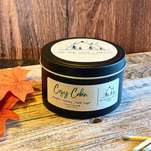 Load image into Gallery viewer, Candle jar labeled 'Cozy Cabin' on a wooden surface with autumn leaves.